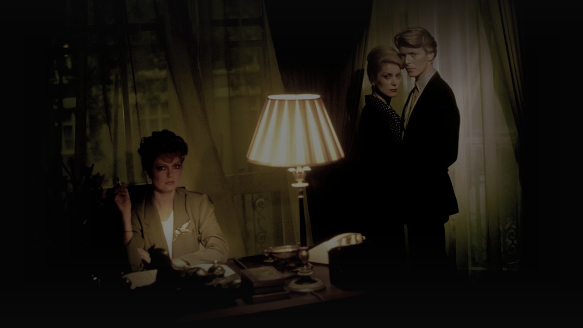 Still from The Hunger (1983) — tmdb backdrop; cross-checked against letterboxd. baked through scripts/bake_dark_photo.py at factor 0.45, 1200x675